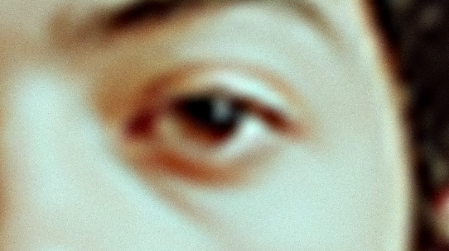 Young dramatic actor's eye in a soft-focus editorial photograph with warm, muted lighting