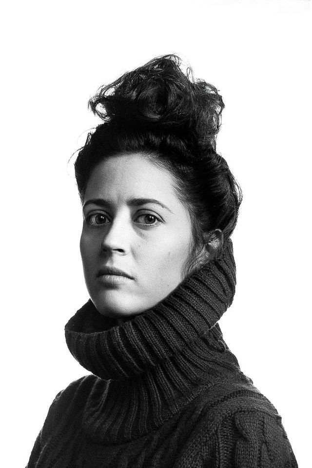 Woman in a chunky turtleneck sweater, stark black-and-white portrait with high contrast