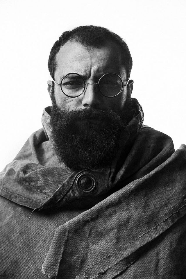 Bearded man in round glasses, stark high-contrast black-and-white portrait