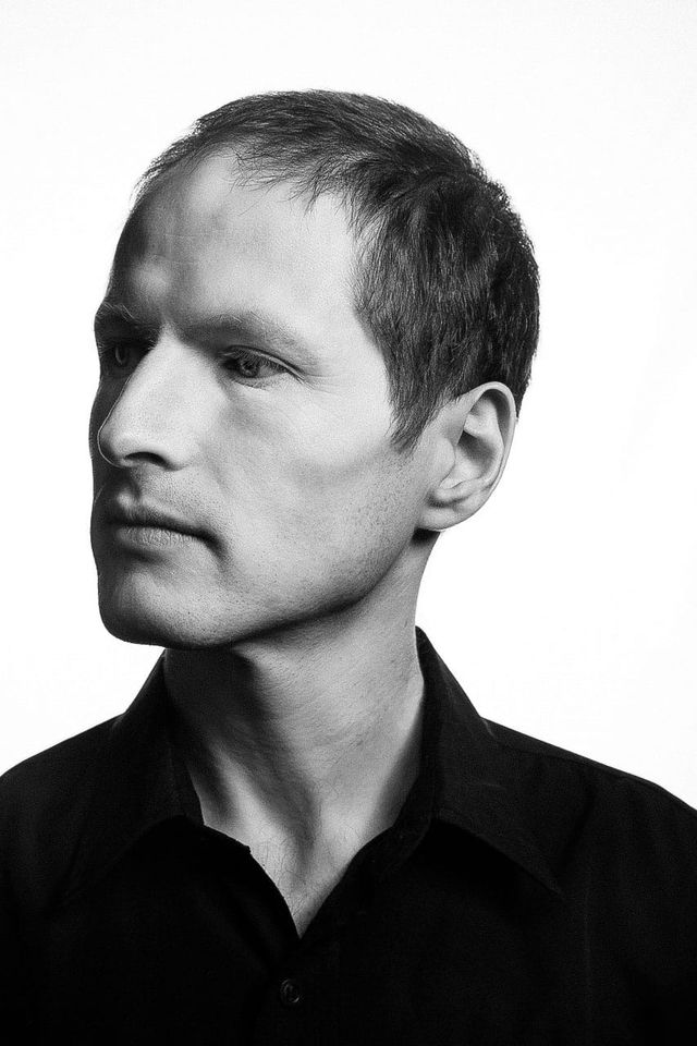 Man’s side-profile portrait in stark black-and-white photography with high-contrast lighting