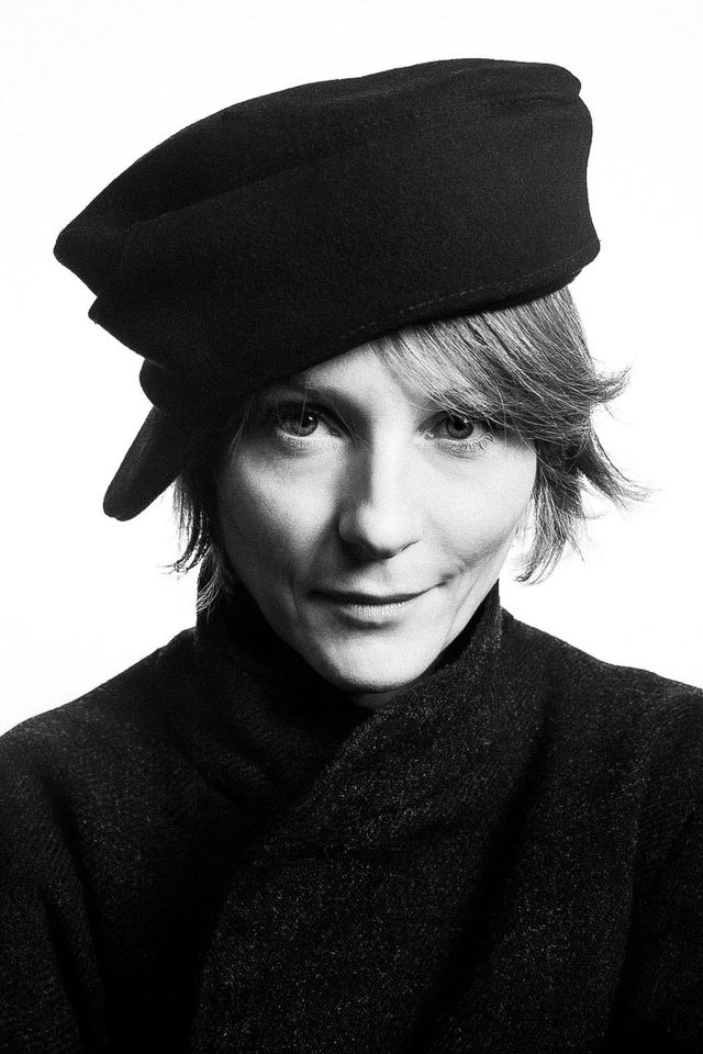 Close-up portrait of a woman in a cap and coat, stark high-contrast black-and-white photography