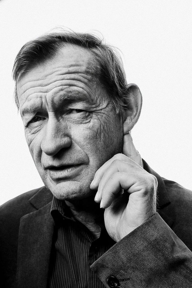Older man touching his neck, rendered as a high-contrast black-and-white portrait photograph