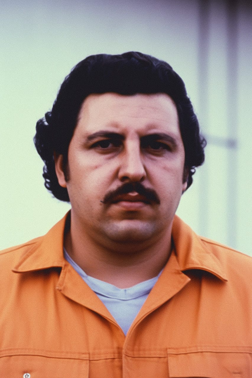 Pablo Escobar in a prison mugshot, grainy court photography with muted colors and flat light, Midjourney V5.2