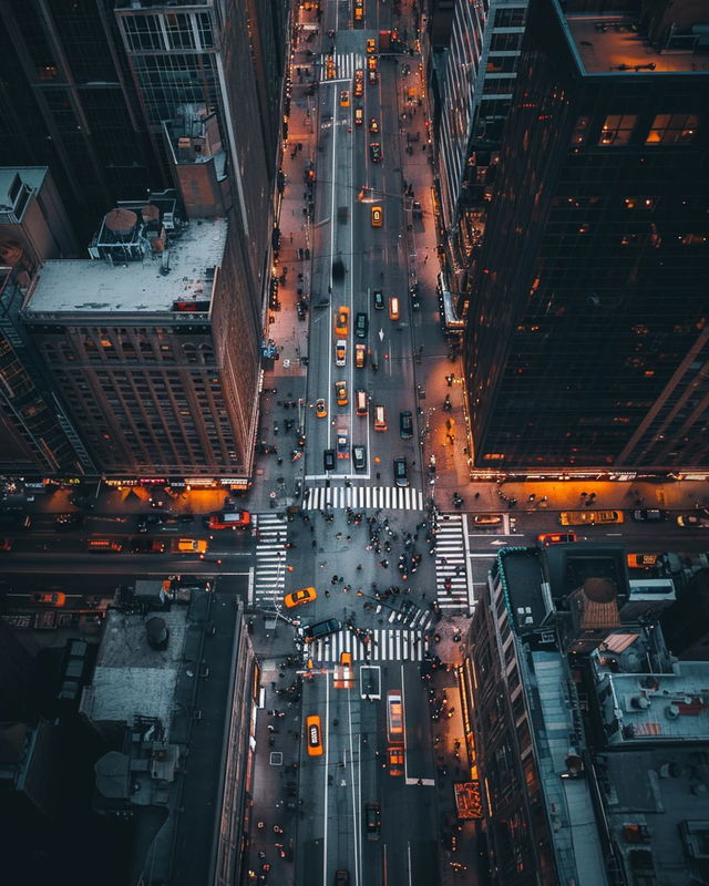 City street seen from above, with traffic and pedestrians in cool blue tones and warm lights, Midjourney V5.2